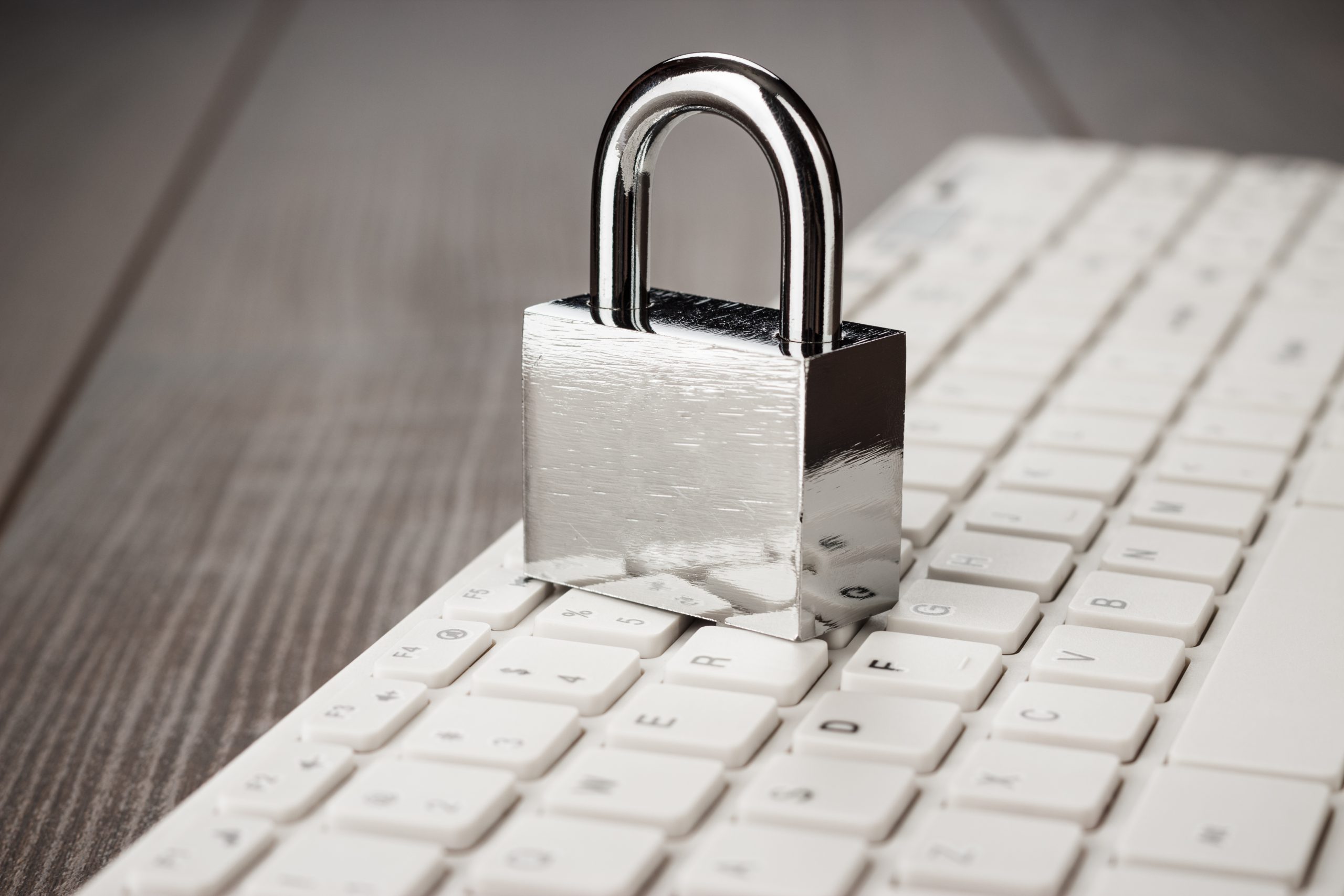 padlock-and-white-computer-keyboard-on-the-wooden--PWWDMLF